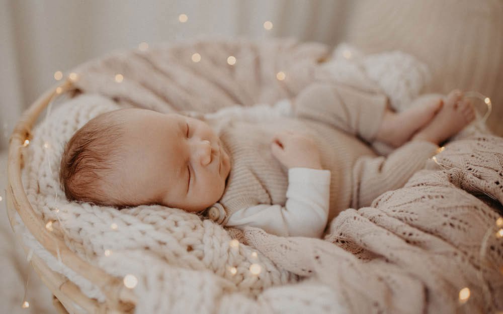 Baby schläft in kuscheligem Weidenkörbchen