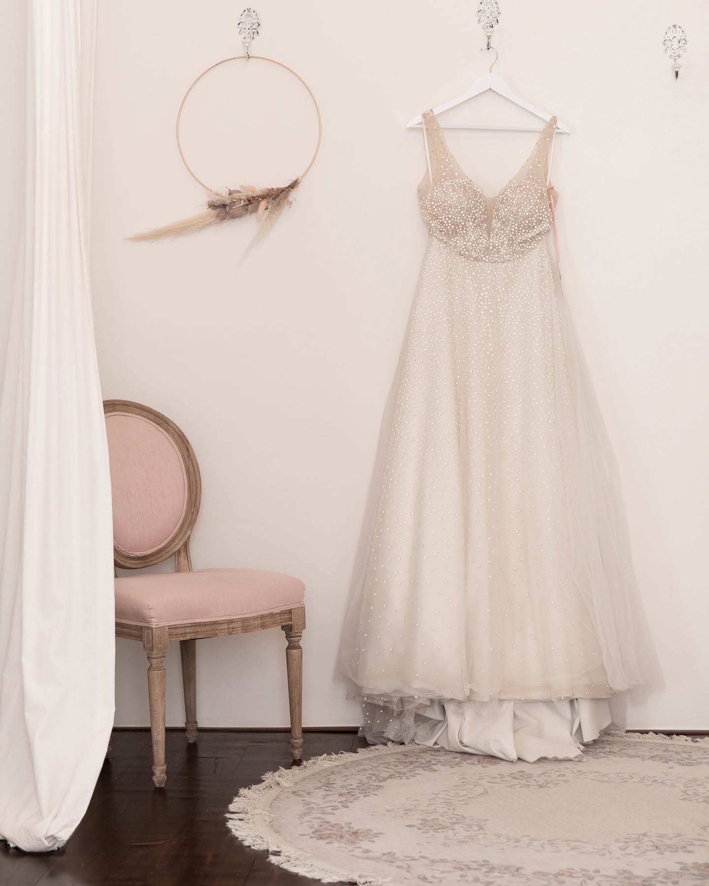 Brautkleid mit Perlen hängt in der Umkleidekabine eines Brautmodenladens.