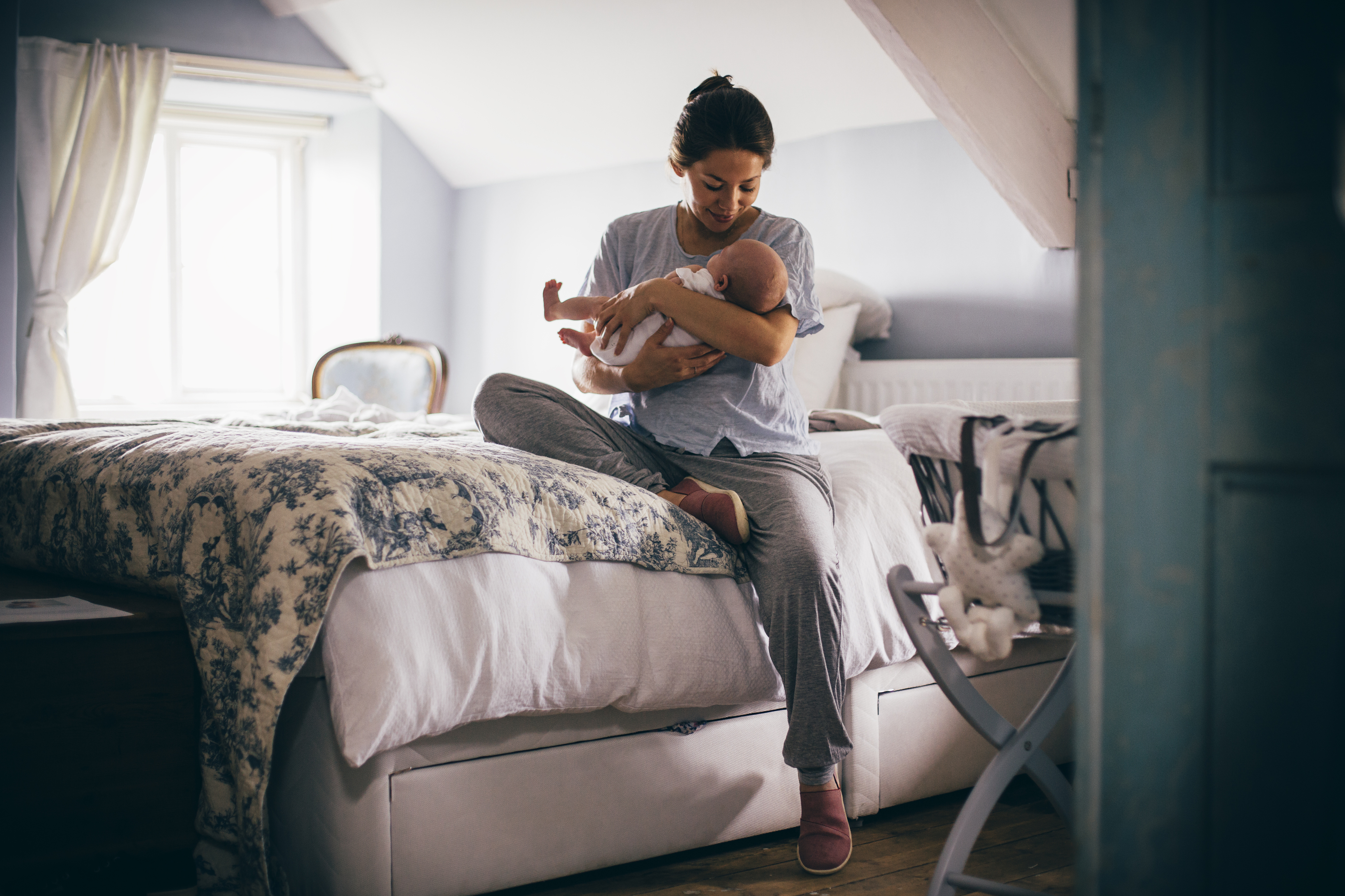 Frau sitzt mit ihrem Baby auf dem Bett