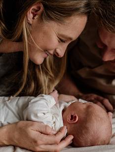 Glückliche Eltern betrachten Baby im Wochenbett