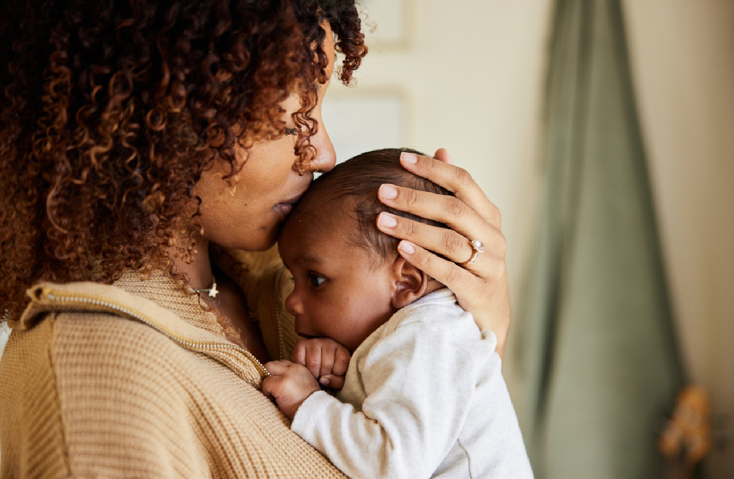 Mutter hält ihr Baby auf dem Arm und küsst es zärtlich