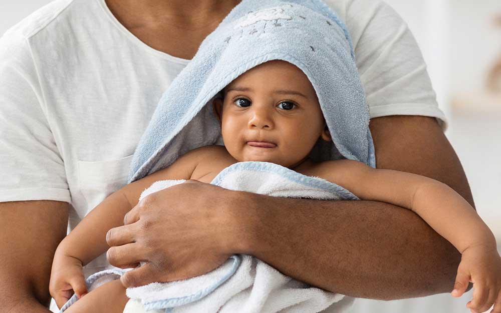 Vater hält frisch gebadetes Baby