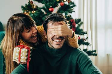 Junge Frau überrascht Mann mit Weihnachtsgeschenk