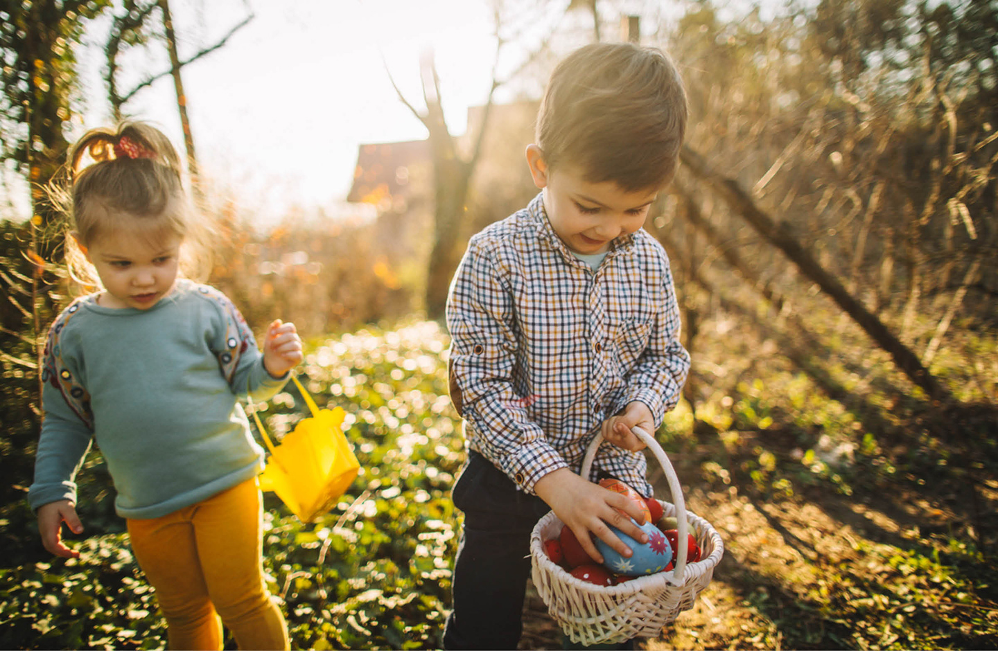 Ein Junge und ein Mädchen sind auf der Suche nach Ostereiern im Garten.