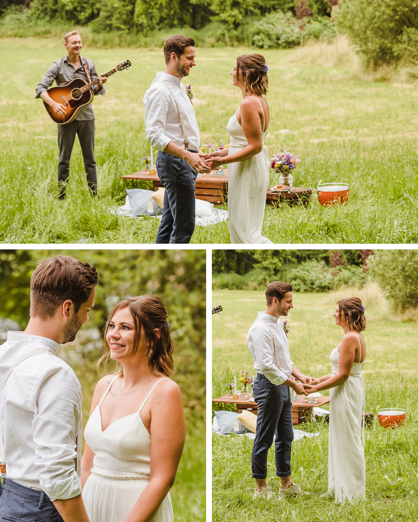Brautpaar hält sich an den Händen und steht auf einer Wiese. Im Hintergrund spielt ein Mann Gitarre und ein Picknick ist aufgebaut.