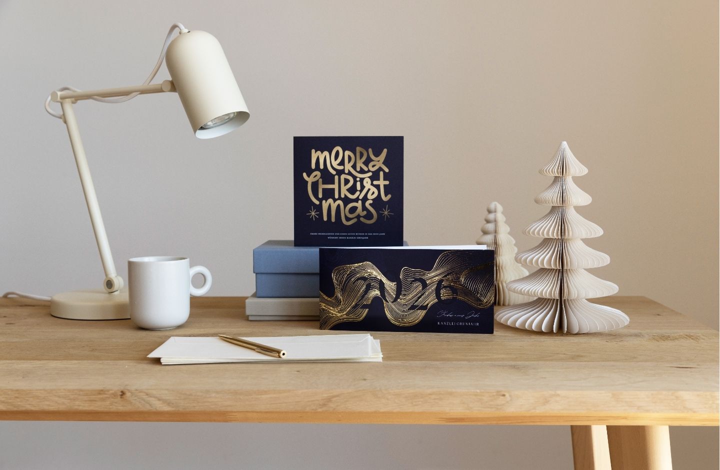 Weihnachtsgrüße geschäftlich mit Goldfolienveredelung auf einem Schreibtisch