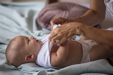 Baby liegt auf dem Wickeltisch und wird gewickelt.