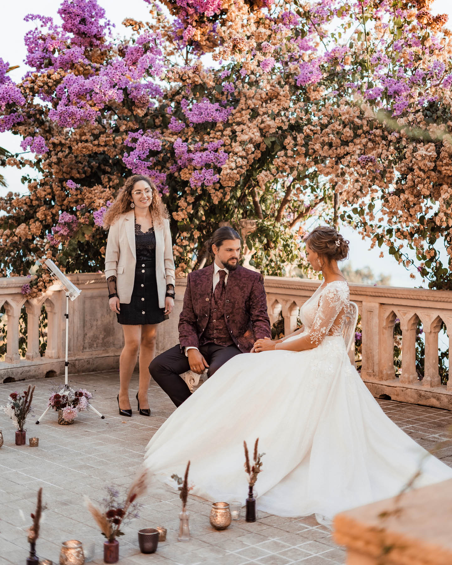 Brautpaar mit Traurednerin auf einer Terrasse mit Bougainvilleen