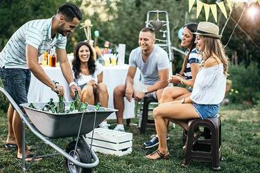 Fünf Freunde sitzen im Garten und feiern glücklich eine Gartenparty.