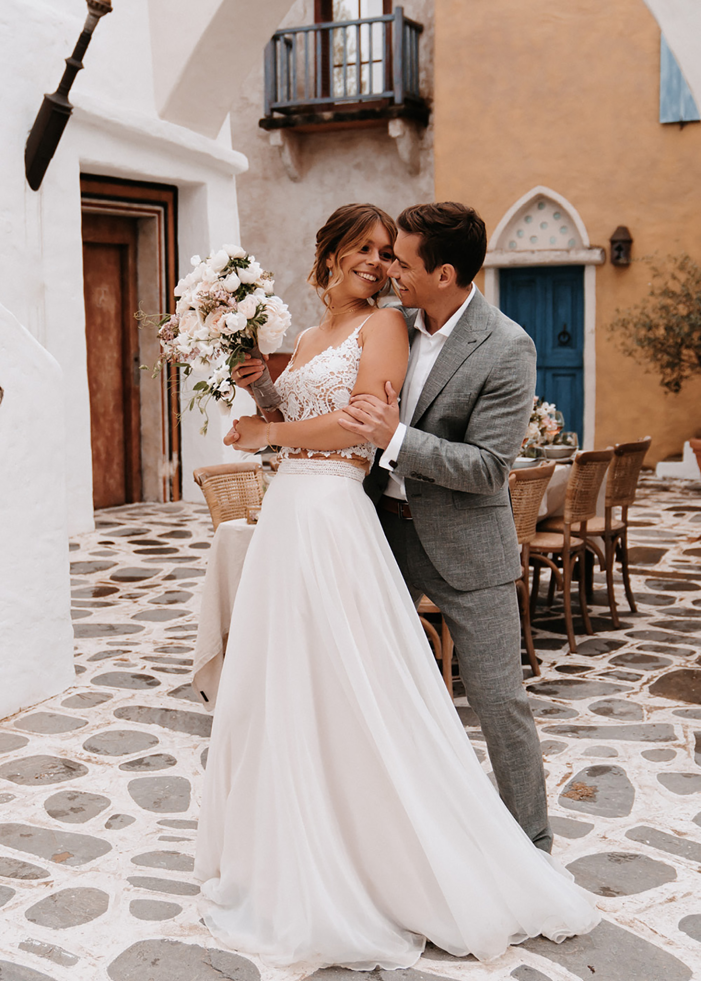 Mediterrane Hochzeit: Das Hochzeitspaar steht vor dem Hochzeitstisch und schaut sich verliebt an. 