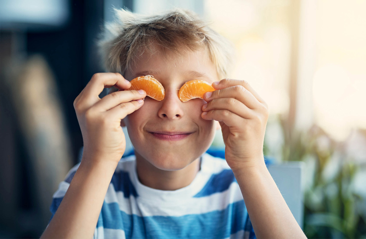 Junge hält sich Mandarinen Spalten vor die Augen.