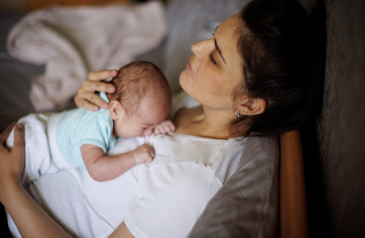 Mutter mit Baby auf dem Bauch ruht sich im Bett aus