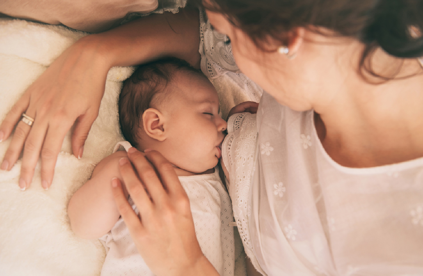 Baby liegt schläfrig an der Brust der Mutter im Bett