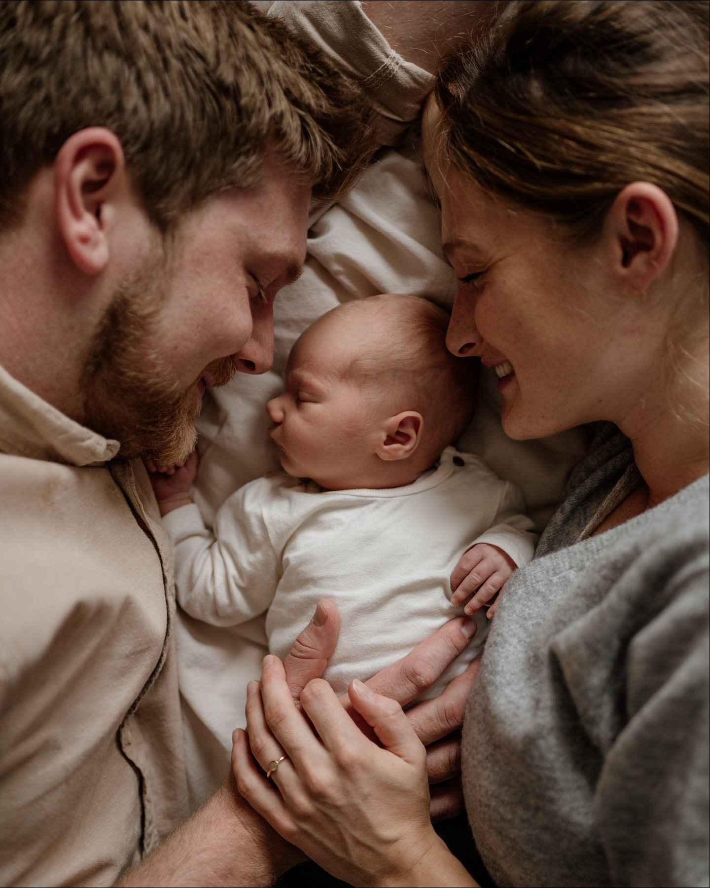 Eltern kuscheln im Bett mit ihrem Neugeborenen