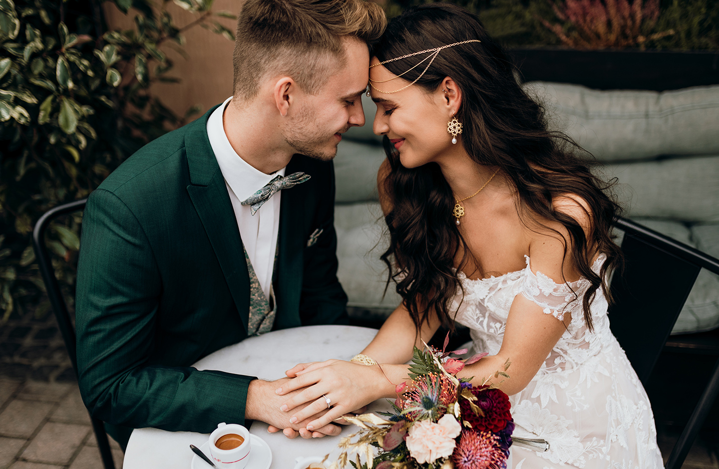 Paar sitzt am Hochzeitstag in einem Kaffee und hält Händchen.