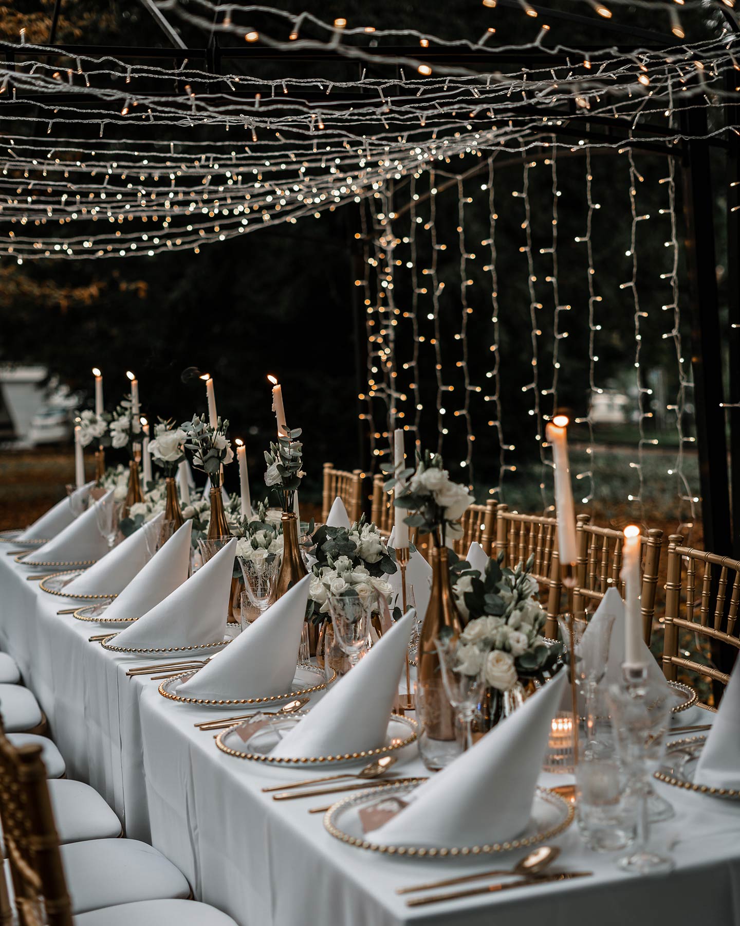 Der Hochzeitstisch im Ganzen ist zu sehen. Die liebevoll angerichtete Tafel in Gold, Weiß und Grün ist bereit für die Gäste.