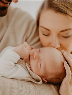 Glückliche Eltern im Wochenbett mit neugeborenem Baby