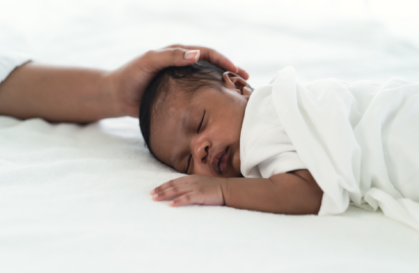 Mutter streichelt zärtlich den Kopf ihres schlafenden Babys