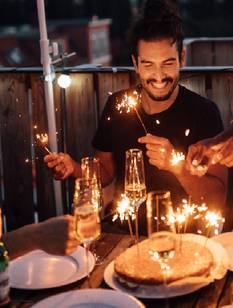 Freunde in den Dreißigern bei einer kleinen abendlichen Geburtstagsparty auf dem Balkon