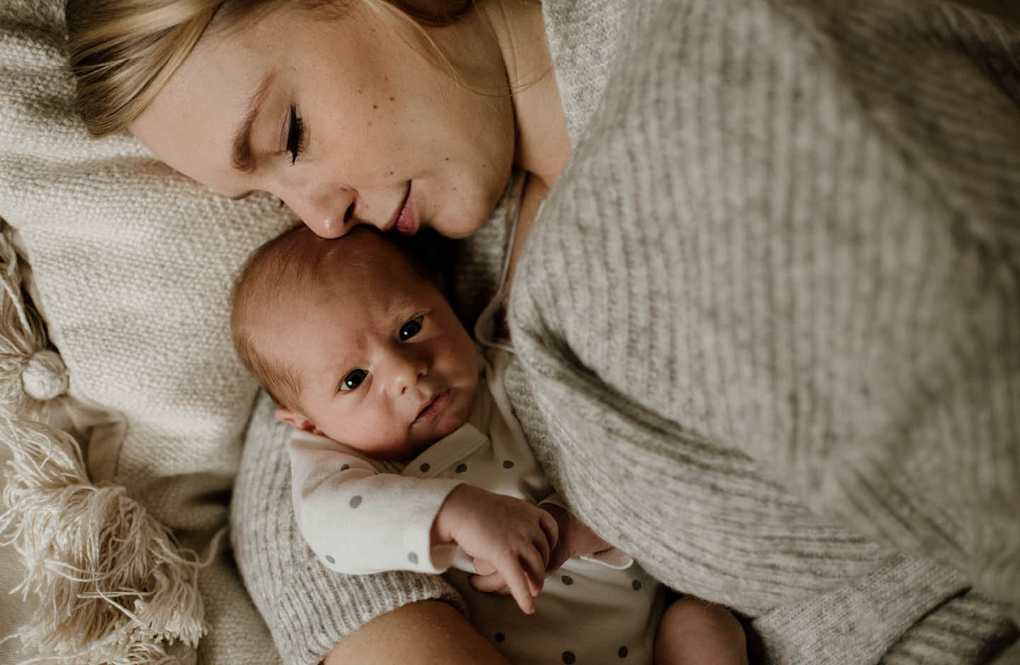 Mutter kuschelt mit Neugeborenem im Wochenbett
