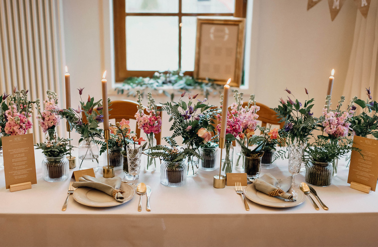 lange festlich geschmückte Hochzeitstafel mit Blumenarrangements und Kerzenleuchter