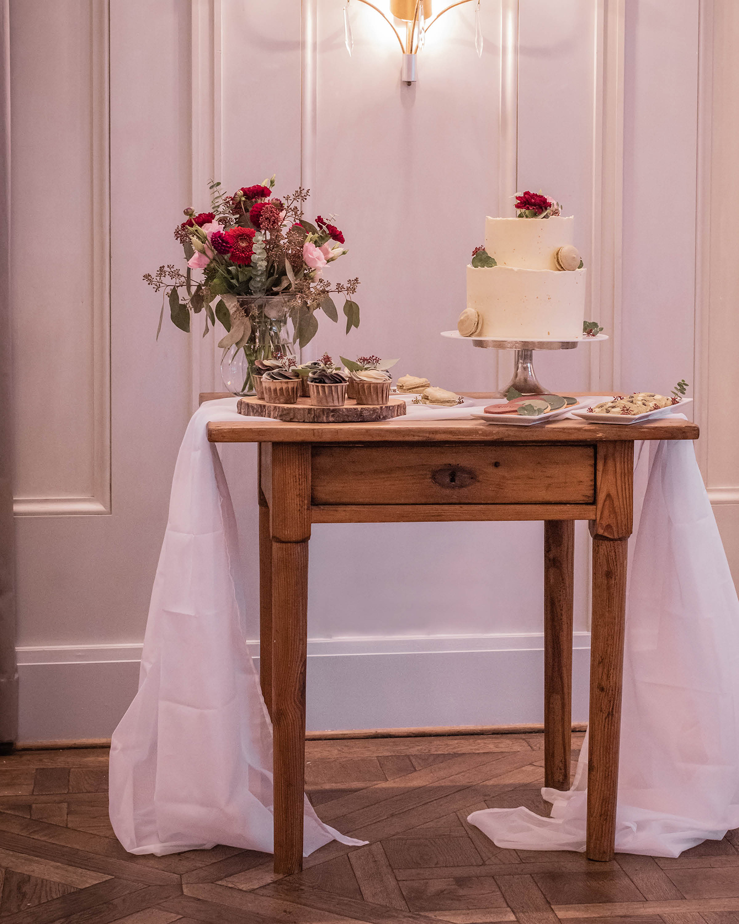 Ein süßes Buffet dekoriert mit der schlichten Hochzeitstorte, handgemachten Keksen und kleinen Cupcakes.
