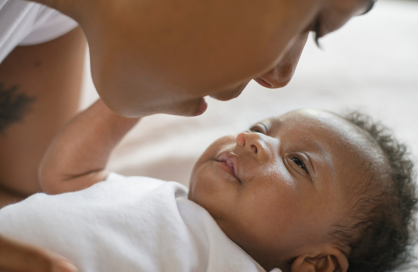 Mutter beugt sich zu ihrem lächelnden Baby hinunter