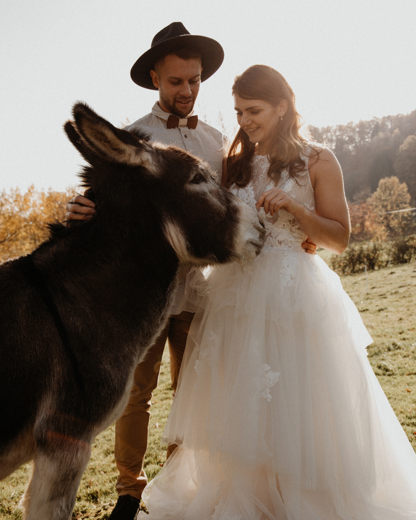 Boho Brautpaar streichelt Esel bei Fotoshooting