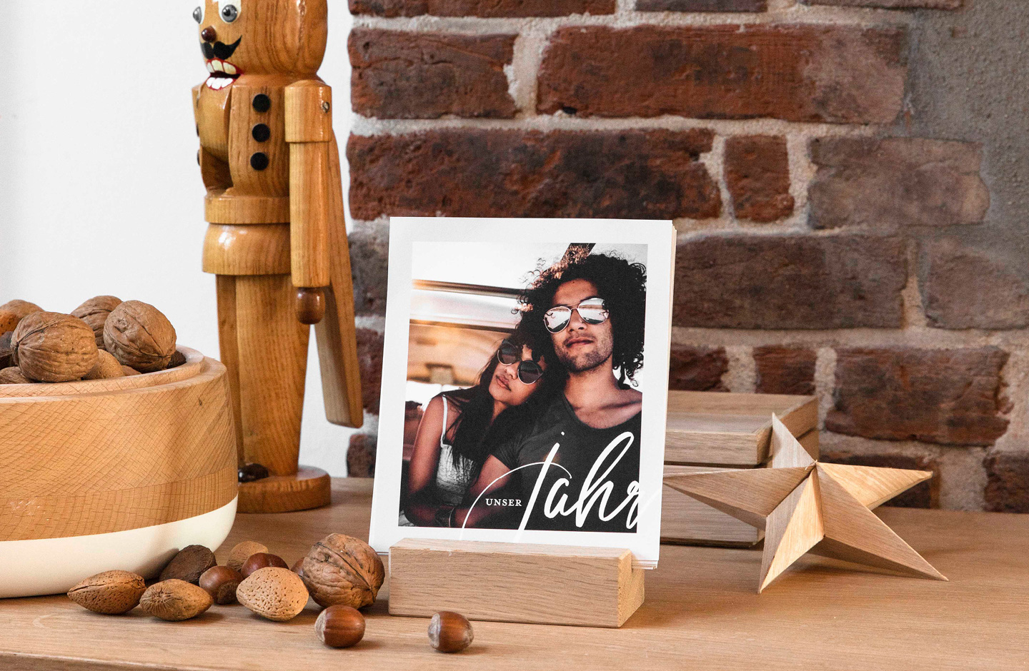 Fotokalender mit Foto von verliebten Pärchen steht auf einem Holztisch und ein Nussknacker steht daneben. 