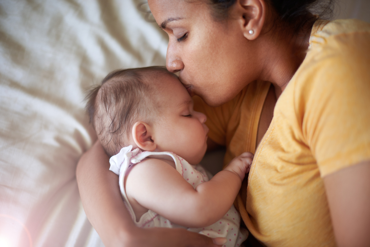 Mama kuschelt im Bett mit ihrem Baby,d as einen amerikanischen Mädchennamen hat
