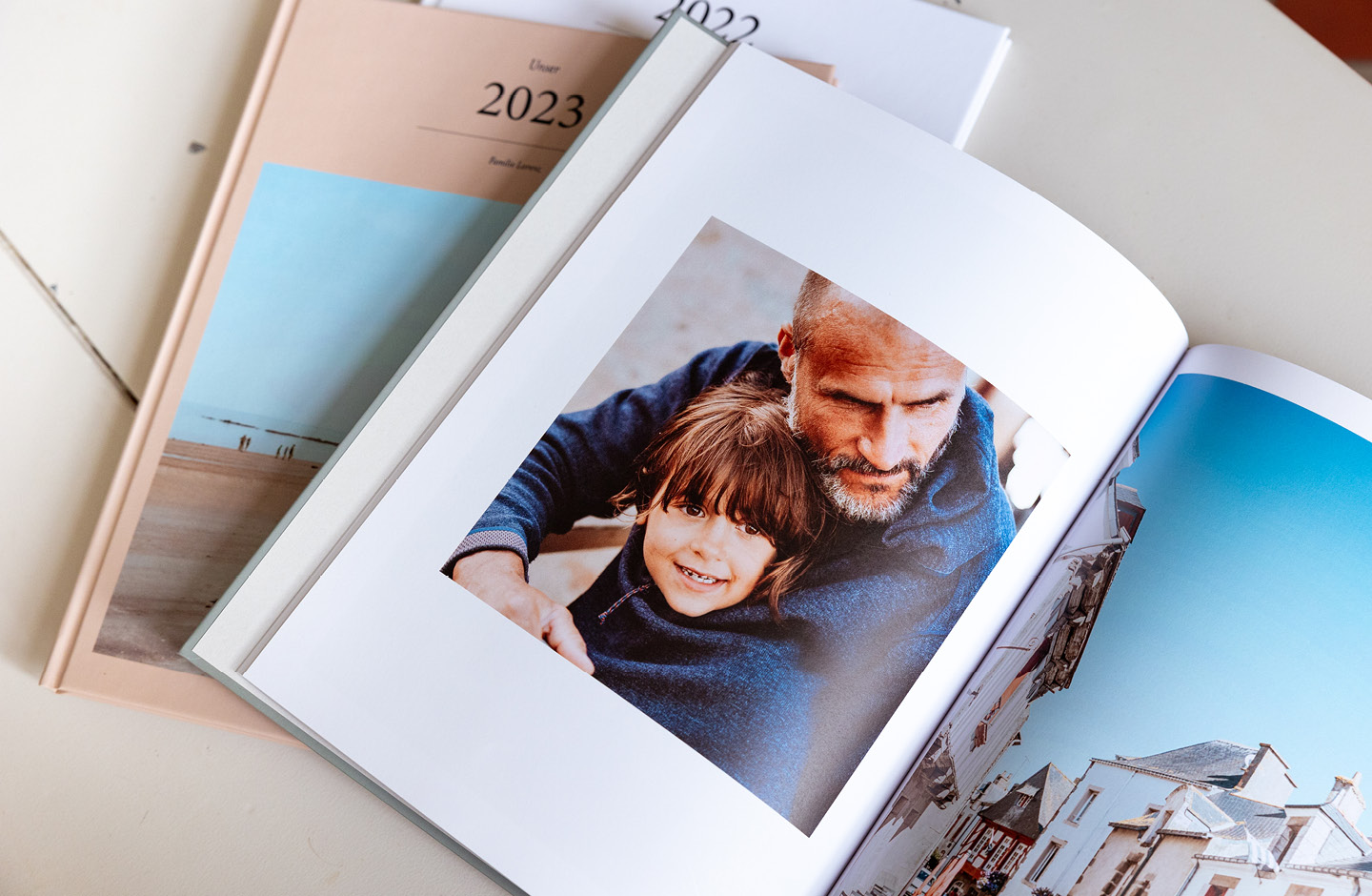 Zwei Fotobücher, eines davon aufgeschlagen mit Urlaubsfotos