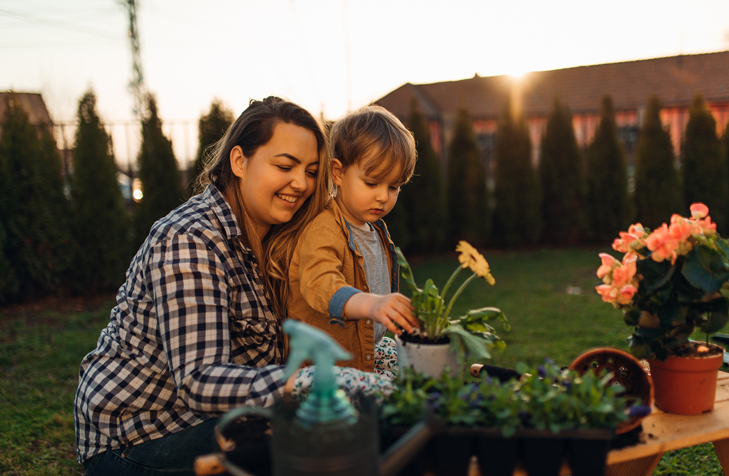 Nachhaltig im Garten als Familie: Baby topft mit ihrem Kleinkind Blumen ein.