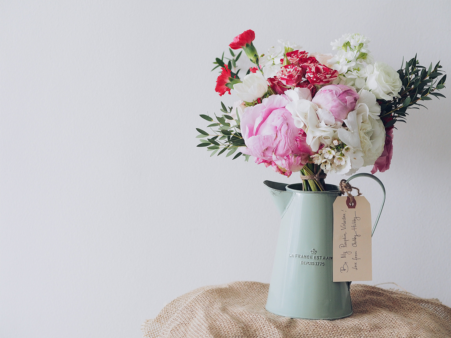 Blumenstrauß mit Pifngstrosen & weißen Rosen wird als Geschenk zum Valentinstag verschenkt.