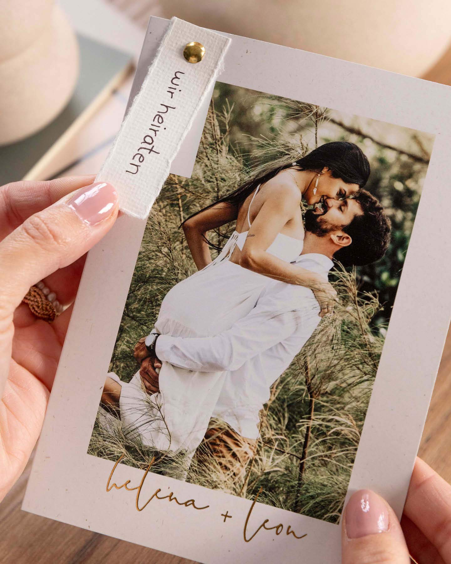 Hochzeitseinladung mit selbst gemachtem Hangtag wird in der Hand gehalten