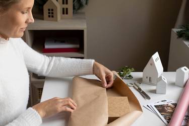 Frau im weißen Pulli packt Geschenk für den Weihnachtsbasar ein