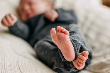 Baby liegt auf Wolldecke.