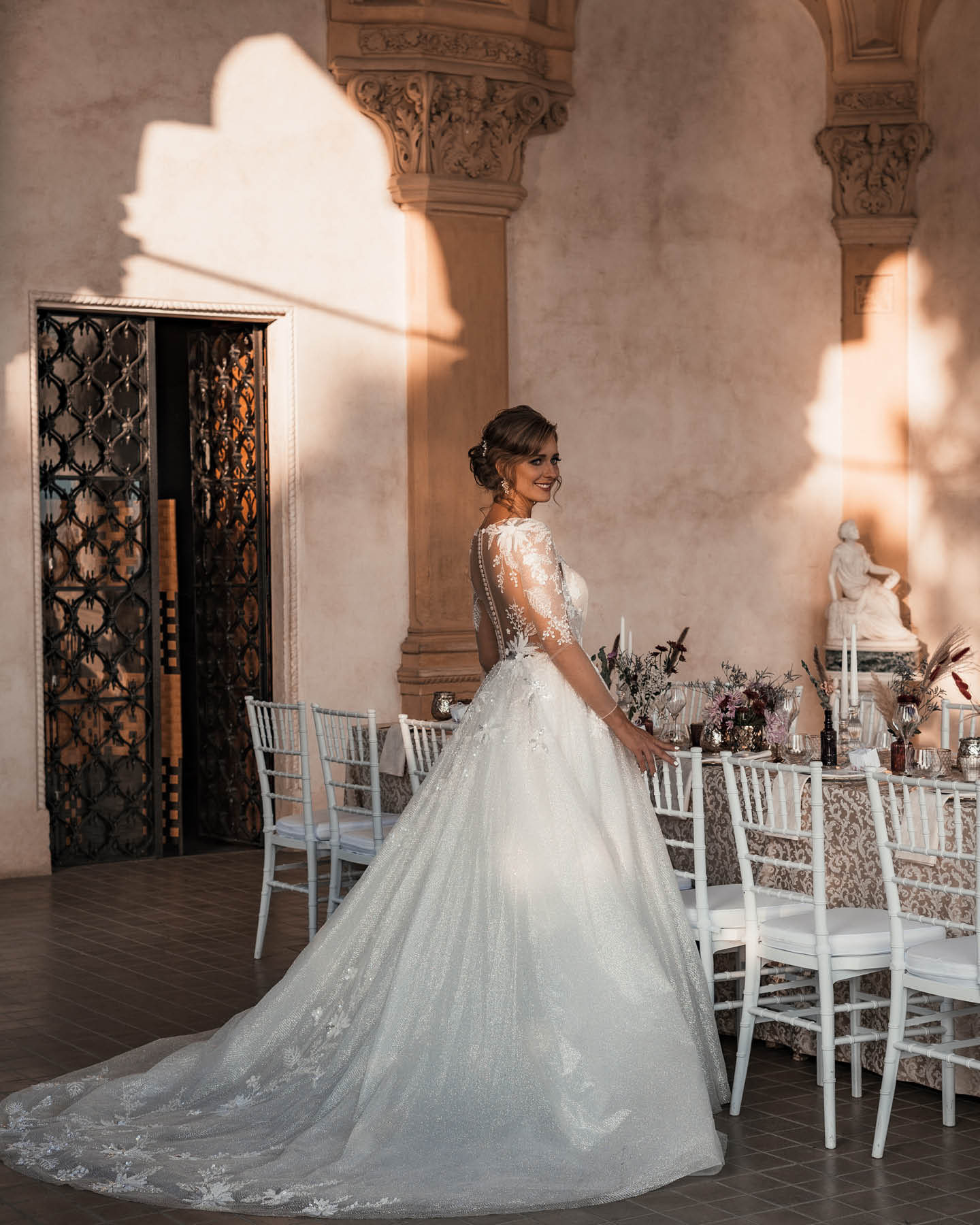 Braut im langen Hochzeitskleid vor der Hochzeitstafel