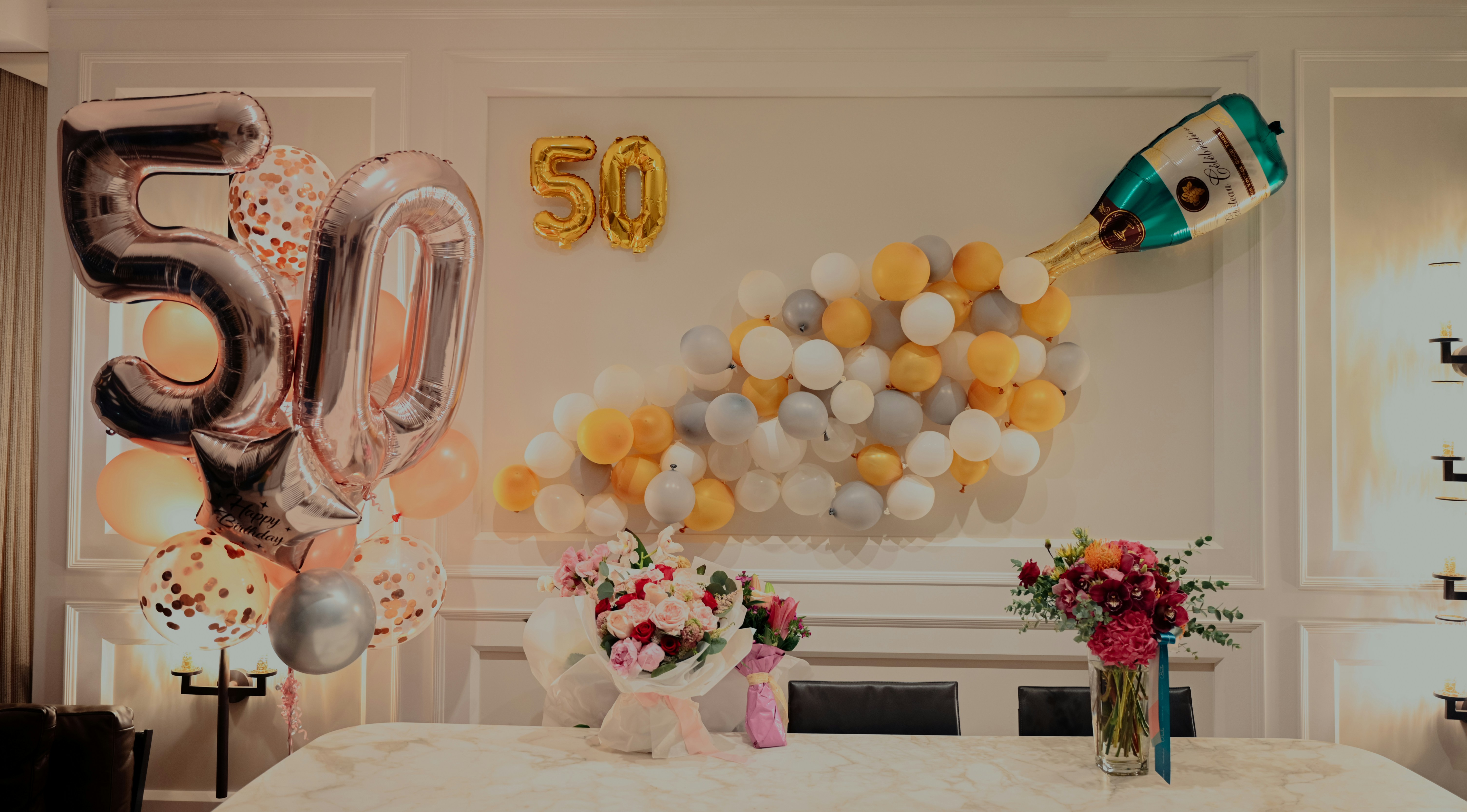 Bild von einer Geburtstagstafel. Im Hintergrund an der Wand sind aufwendige Dekorationen aus Ballons zu sehen sowie eine 50.