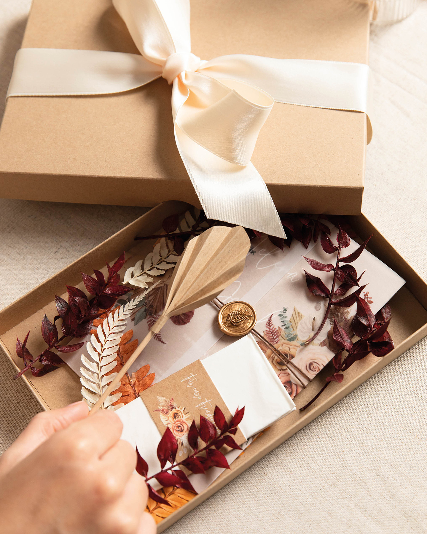 Hochzeitseinladung selber basteln in einer Überraschungsbox für die Gäste: Trockenblumen, Hochzeitseinladung, DIY-Palmenblätter und ein Taschentuch für die Freudentränen zieren die Box
