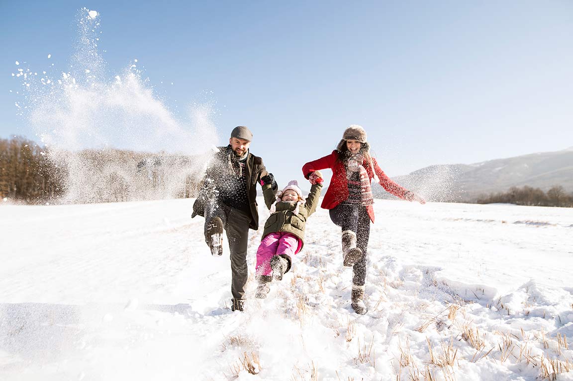 Winterfoto: Eltern mit Kind an der Hand spielen im Schnee