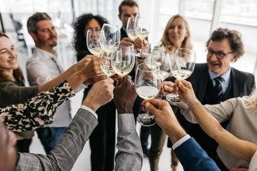 Arbeitskolleg:innen stoßen mit Wein an.