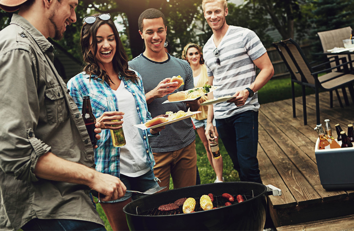 Freunde stehe zusammen am Grill